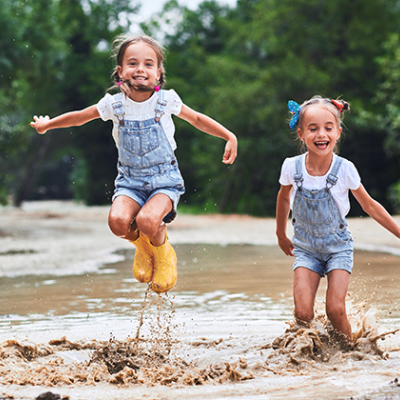 Twin girls jumping in a stream